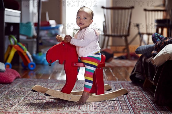 Mixed race baby girl playing on rocking horse