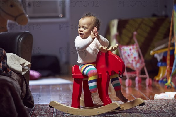 Mixed race baby girl playing on rocking horse