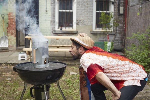 Caucasian man lighting charcoal for grill in backyard