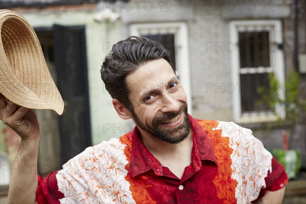 Caucasian man tipping straw hat in backyard