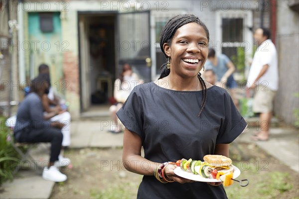 African American woman eating at backyard barbecue