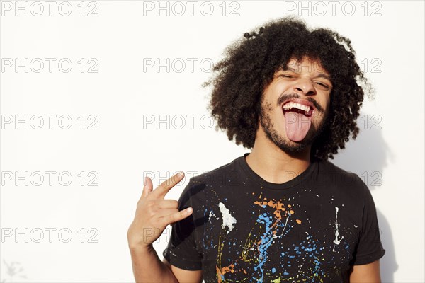 Mixed race man making a face and rock-on hand gesture