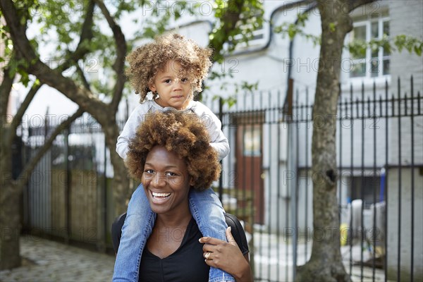 Mother carrying daughter on shoulders outdoors
