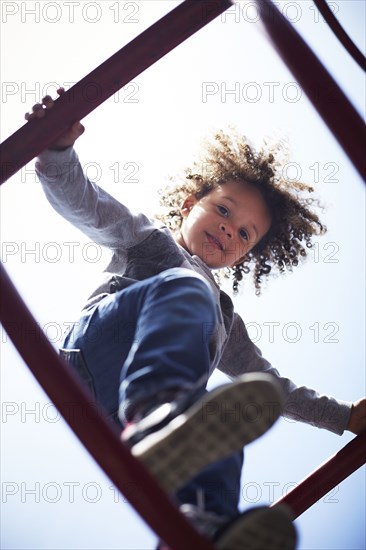 Low angle view of mixed race boy climbing on play structure