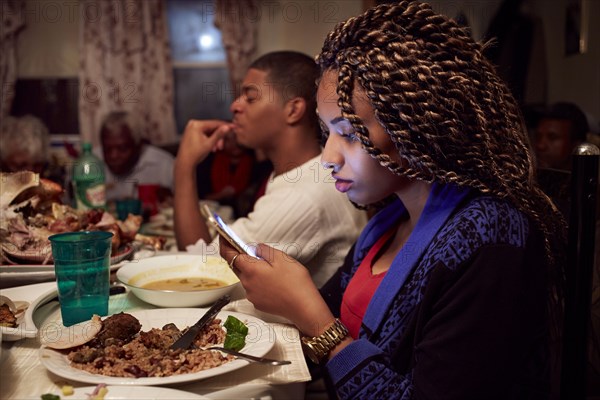 Teenage girl using cell phone at dinner table