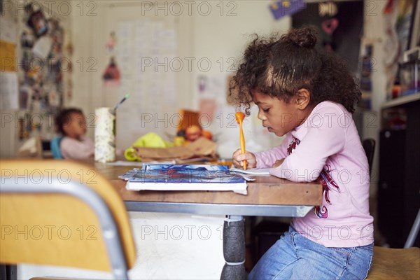 Mixed race girl drawing at table