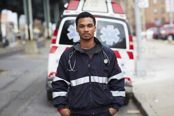 Mixed race paramedic standing near ambulance