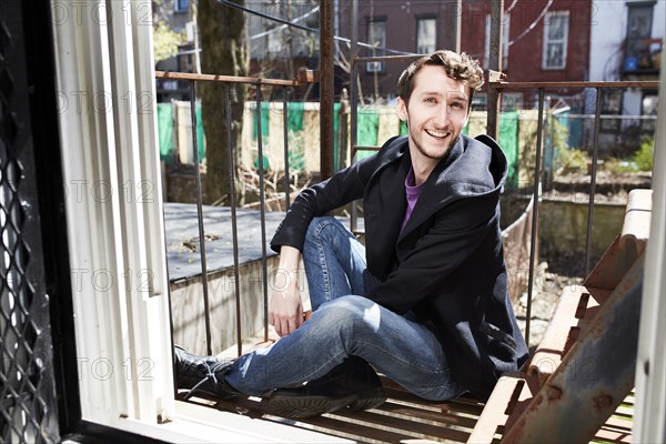 Caucasian man sitting on fire escape