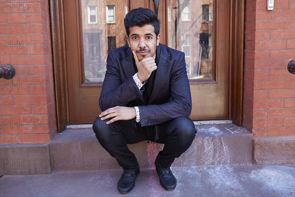 Middle Eastern man sitting on front stoop