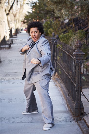 Mixed race man in defensive pose on sidewalk