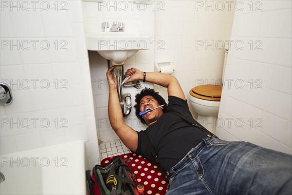 Mixed race man fixing sink plumbing