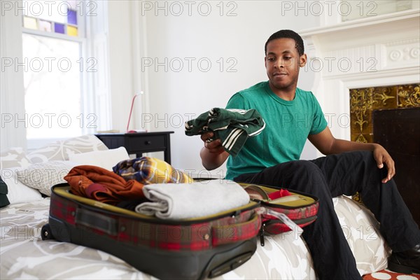 African American man packing suitcase in bedroom