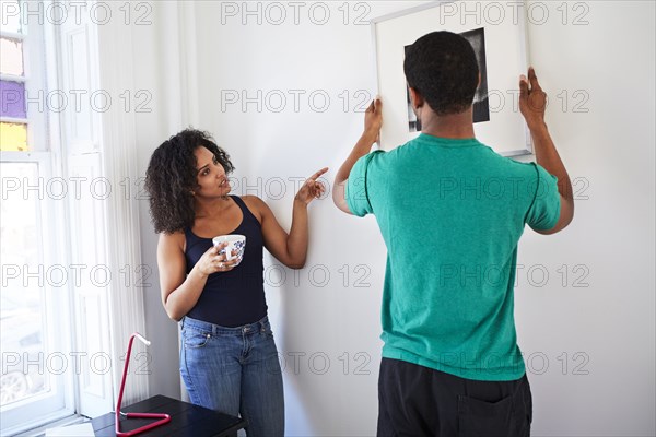 Couple hanging picture in new apartment