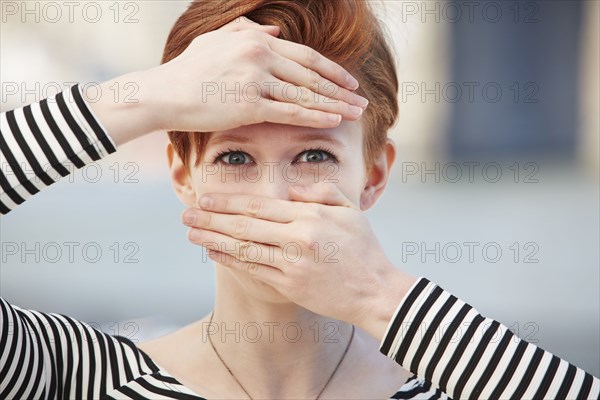 Caucasian woman covering mouth and forehead with hands