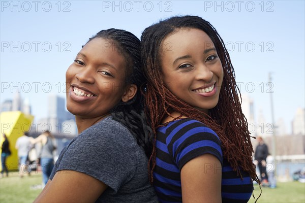 Smiling Black women sitting back to back