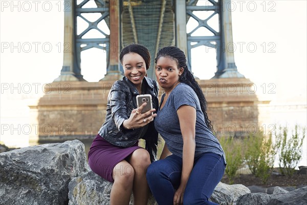 Black women posing for selfie at bridge