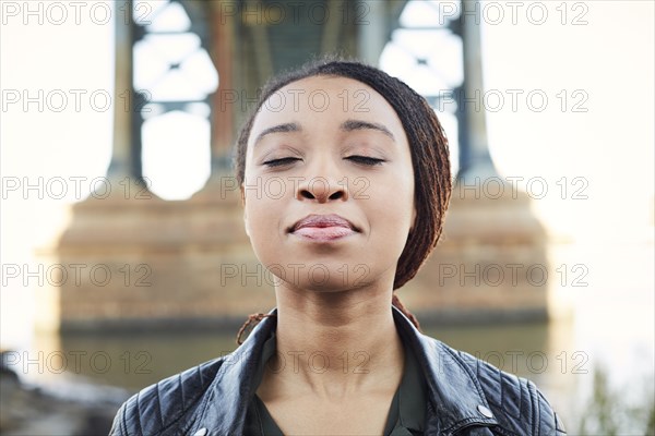 Black woman thinking with eyes closed at bridge