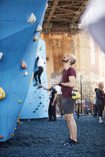 Hispanic man looking up at outdoor climbing wall