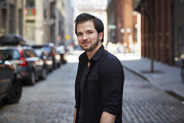 Caucasian man smiling on cobblestone city street