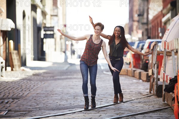 Women balancing on track in cobblestone city street