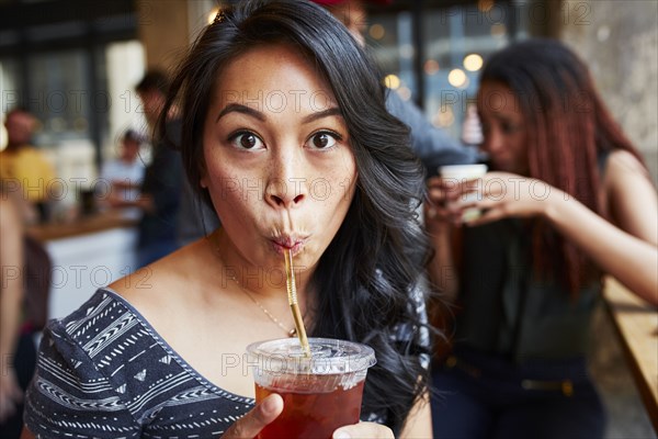 Woman drinking cold drink with straw in cafe