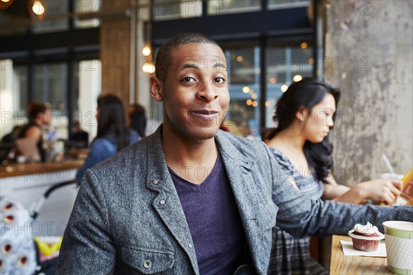 Smiling man with coffee and cupcake at coffee shop