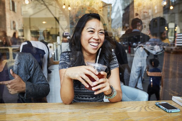 Mixed Race woman smiling in cafe window