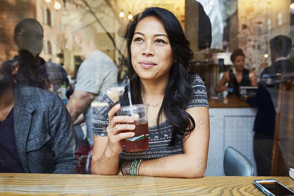 Mixed Race woman thinking in cafe window
