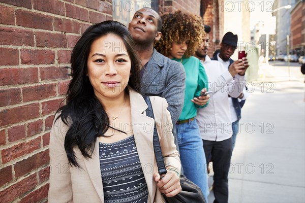 People waiting in line on sidewalk with cell phones