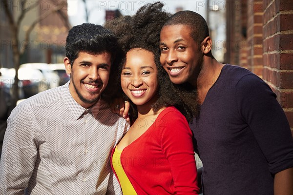 Smiling friends posing on city sidewalk