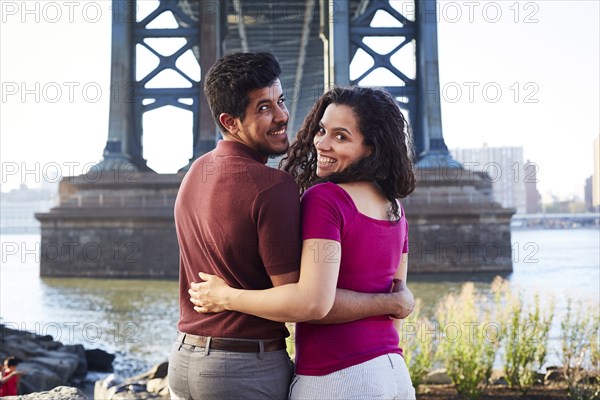 Hugging couple smiling at waterfront