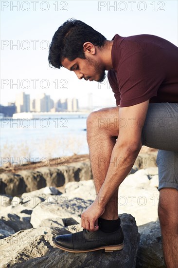 Middle Eastern man tying shoelace at waterfront