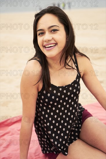 Mixed Race woman sitting on blanket at beach