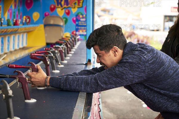 Man playing shooting game at amusement park