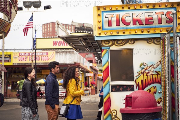 Friends waiting in line at amusement park ticket booth