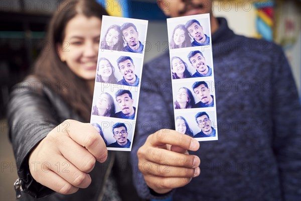 Couple showing photograph strips from photo booth