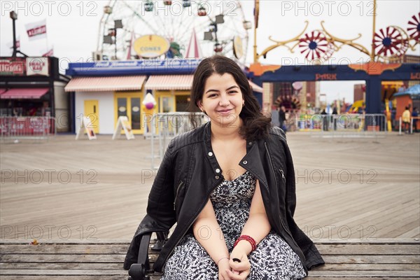 Mixed Race woman sitting on bench at amusement park