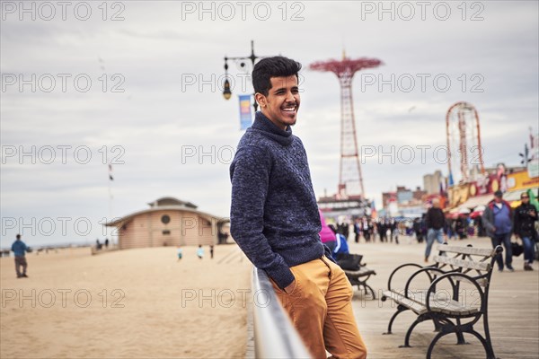 Man leaning on boardwalk railing at beach