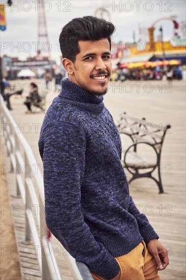 Man leaning on boardwalk railing at amusement park