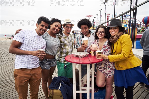 Friends drinking coffee on boardwalk at beach