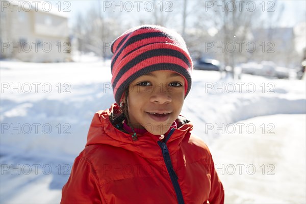 Smiling Mixed Race girl wearing hat and coat in winter