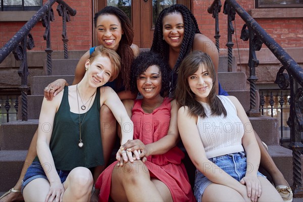 Smiling women sitting on urban front stoop