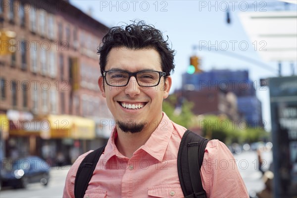 Hispanic man wearing backpack in city