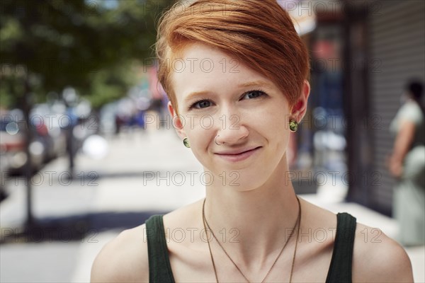 Caucasian woman with nose ring smiling on city sidewalk