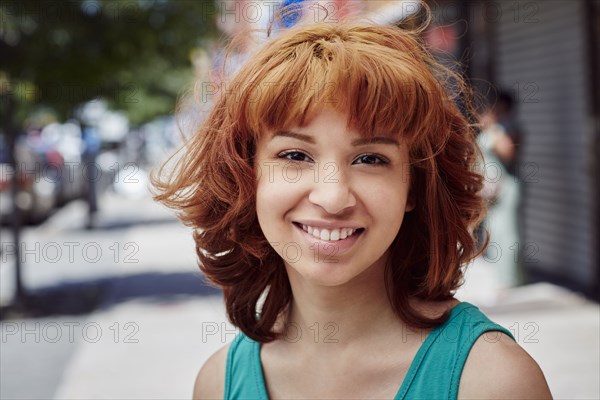 Hispanic woman smiling on city sidewalk