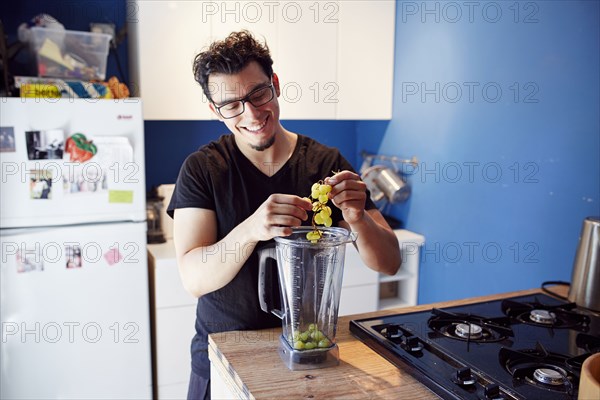 Hispanic man putting grapes in blender