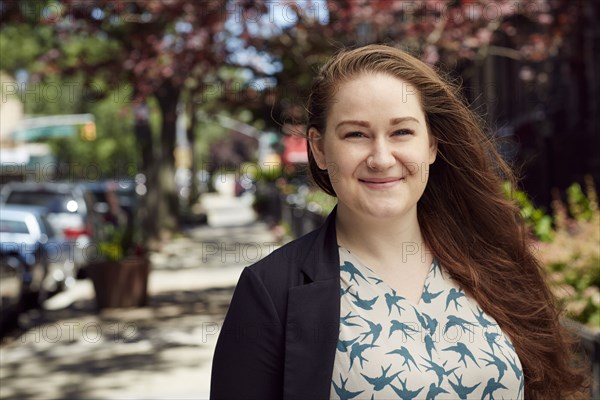 Wind blowing hair of Caucasian woman on city sidewalk