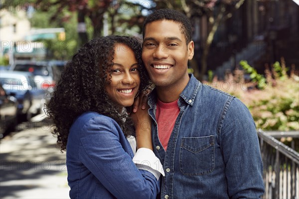 Smiling couple posing on city sidewalk