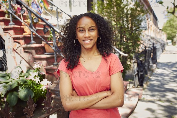 Smiling Mixed Race woman posing on city sidewalk