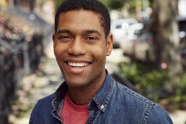 Smiling man posing on city sidewalk